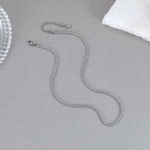 Collier chaîne torsadée en acier inoxydable argenté minimaliste sur une surface grise