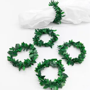 Close-up of green vine wreath napkin rings on white fabric with artificial leaf texture