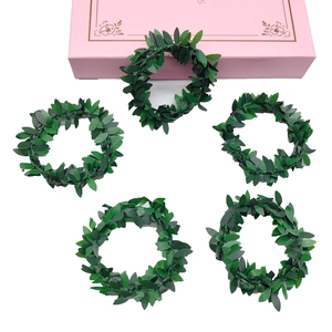 Detailed view of five artificial green leaf napkin rings arranged on a white surface