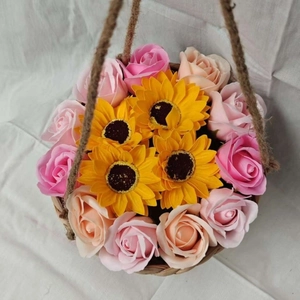 Hanging woven plant basket with pink roses and yellow sunflowers on white linen
