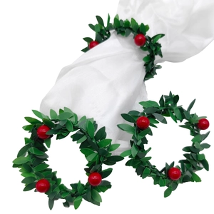 Detail showing artificial Christmas holly leaf and red berry napkin ring on white fabric