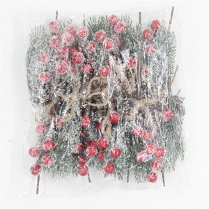 Detail of Christmas artificial pine branch with red berries and faux snow in packaging