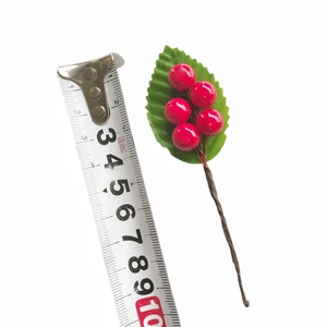 Artificial red berry sprig with green leaf and measuring tape on white background