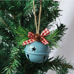 Blue metal Christmas bell with star cutouts and pine cone hanging on a tree