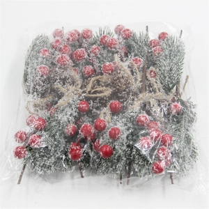 Detail of snowy artificial pine needles, red berries, and pine cones in clear packaging
