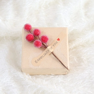 Detail der Kraftpapier-Geschenkbox mit roten Beeren auf weichem weißem Kunstfell