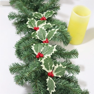 Artificial Christmas pine garland with red berries and holly leaves on white background