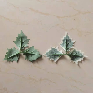 Detail of artificial holly leaves featuring frosted green and white snow-flocked textures