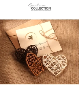 Détail de pendentif oiseau en bronze sur carte avec décor en jute et cœurs en rotin tressé