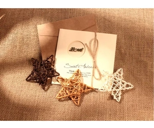Détail d'étoiles en rotin tressé, carte de vœux et enveloppe en kraft sur toile de jute