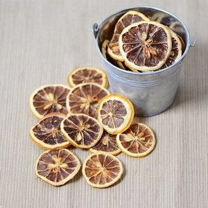 Natural dried lemon slices on beige cloth with a rustic zinc bucket decoration