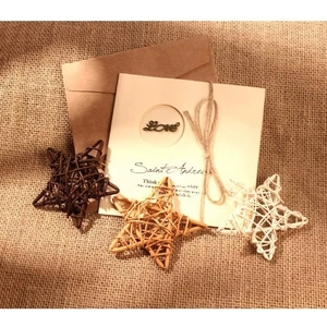 Étoiles en rotin tissé marron et blanc avec carte de vœux rustique sur toile de jute