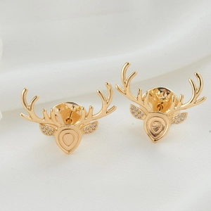 Elegant pair of gold antler brooches with sparkling crystals on white silk background