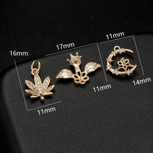 Detailed view of three gold pendants with micro-pave zircons on a black leather surface