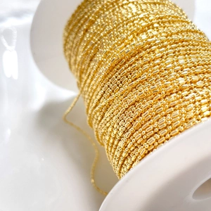 Polished 14K gold bead and bar chain accessory neatly wound on a white spool for DIY jewelry