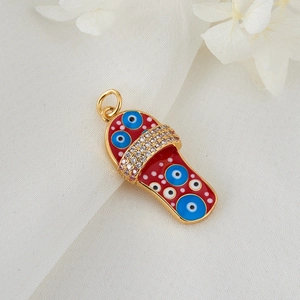 Golden slipper pendant with red enamel evil eye design and pavé stones on fabric