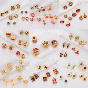 Macro detail of Chinese persimmon and lotus enamel charms with gold finish and vibrant colors