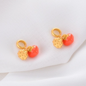 Detailed close-up of gold sand persimmon and lotus root pendants on white fabric