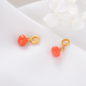 Macro view of gold sand-finish metal and orange enamel persimmon charms for DIY bracelets