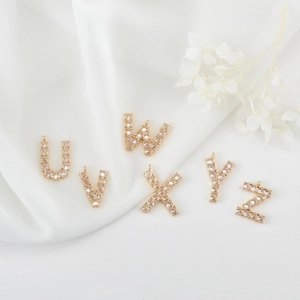 Detail van 14K vergulde zirkonia letterhangers U-Z op witte zijden achtergrond