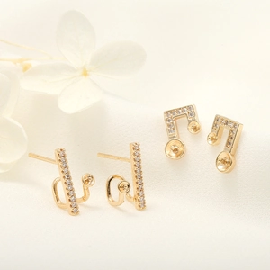 Macro view of gold-plated bar and music note earrings with zircon for jewelry DIY
