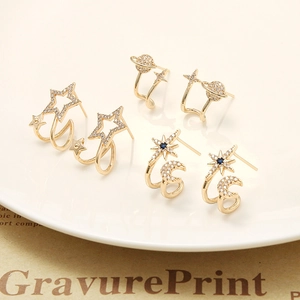 Detailed macro view of gold star, moon and Saturn stud earrings set with zircon stones