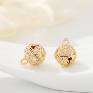 Macro shot of 14k gold plated hollow bell pendants with intricate scrollwork patterns