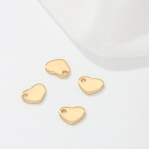 Detailed view of four heart-shaped 14k gold plated copper pendants with hanging holes