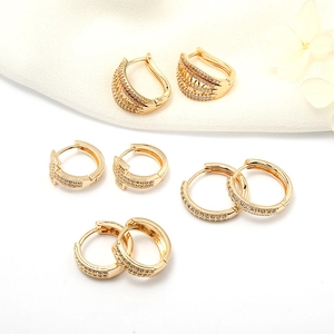 Macro shot of 14k gold-plated brass earring set with cubic zirconia on white fabric