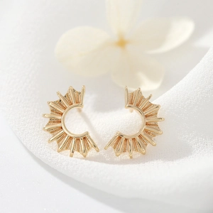 Elegant gold plated half-round sunburst stud earrings on white textured fabric background