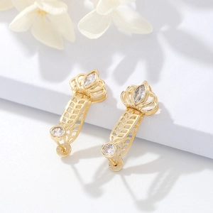 Detalle de pendientes de corona bañados en oro 14K con circonitas y patrón de hojas