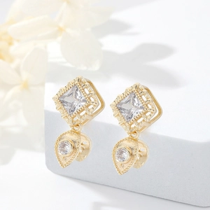 14k gold plated square zircon earrings with teardrop pendants on white stone display