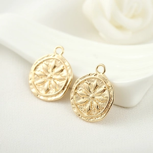 Macro shot of 14k gold-plated round charms with floral relief for DIY jewelry making