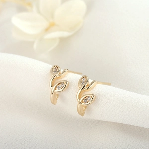 Gros plan de boucles d'oreilles feuilles dorées 18 carats avec détails floraux en zircone