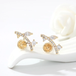Macro detail of gold branch stud earrings with clear zircon stones and tray settings