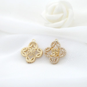 Macro detail of 14K gold-plated four-leaf flower pendants with zircon pavé and hollow back