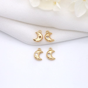 Detailed view of four golden crescent moon pendants with cubic zirconia for jewelry making