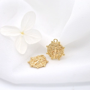 Detailed macro view of 14k gold plated copper coin pendants with classical embossed relief