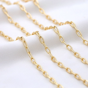 Polished 14K gold plated oval paperclip chain necklace on white wrinkled fabric