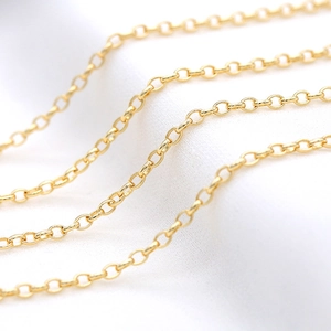 Makroaufnahme einer 14K vergoldeten Rolo-Kette mit glattem Metallglanz auf Leinenhintergrund
