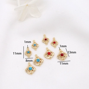 Detail view of gold-plated flame pendants with red and turquoise stone inlays
