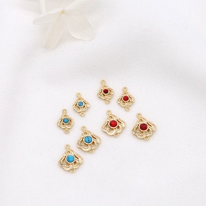 Detailed view of 14K gold-plated flame pendants with red and turquoise stones for DIY