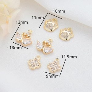 Detailed view of 14K gold plated charms with swan, paw print and clover designs