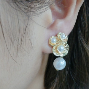 Detailed macro shot of 14k gold plated leaf earring with white pearls on a model