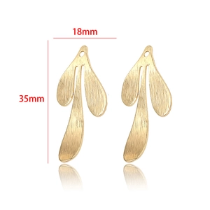 Detalle macro de colgantes de hoja bañados en oro de 14k con textura cepillada de 35x18mm