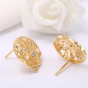 Macro detail of 14k gold plated shell earrings with pearls, zircons and hanging loop