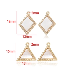 Macro detail of geometric gold charms in rhombus and triangle shapes with pearl edges