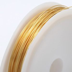 Fil artisanal doré brillant pour fabrication de bijoux enroulé sur une bobine blanche
