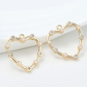 Detailed view of 14k gold plated heart-shaped pendants with pearls and zircons