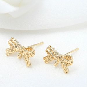 Macro detail of 14k gold plated bow-shaped jewelry connectors with lace texture